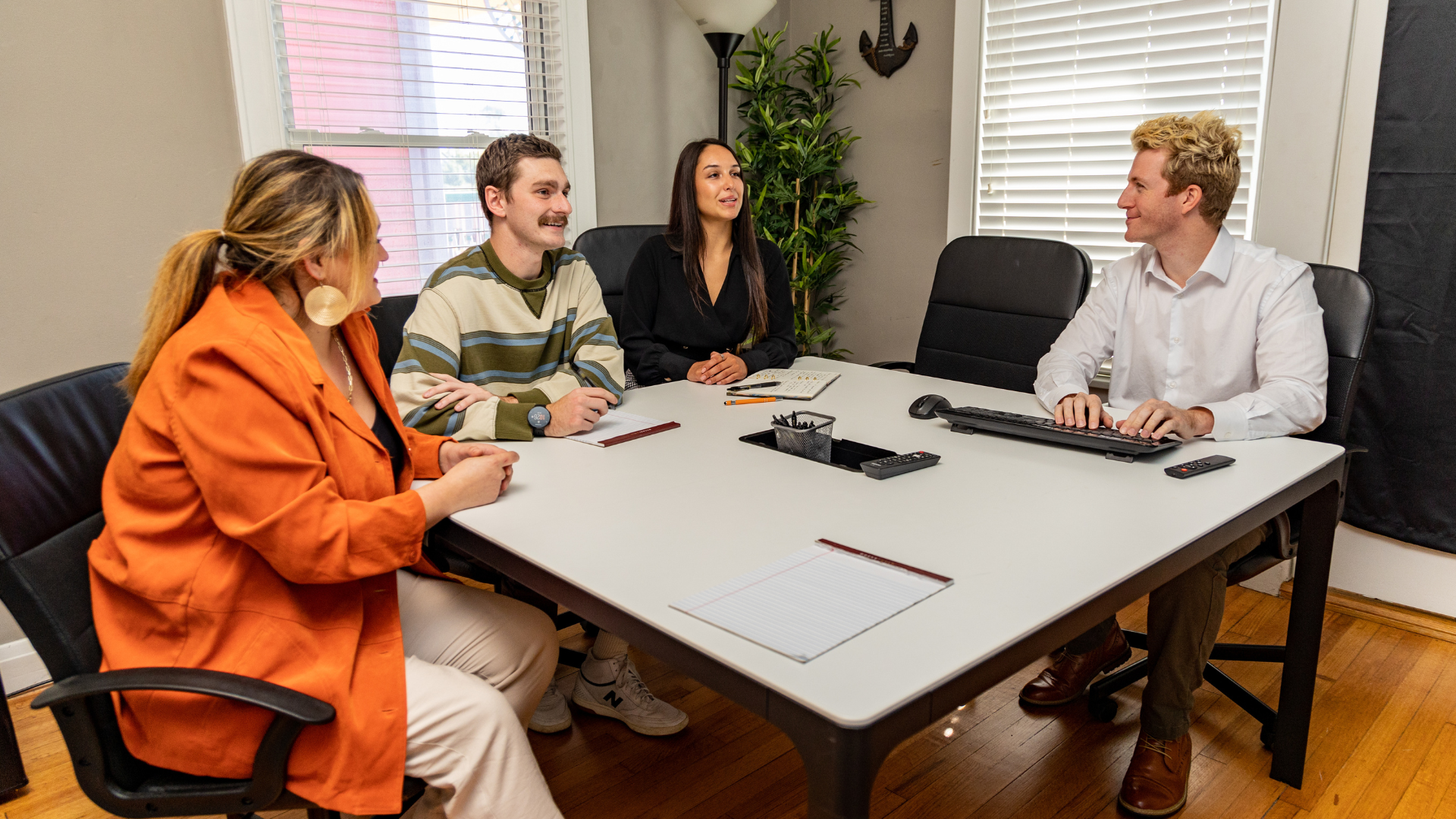 The team collaborating around a table, candid, real office. Warm, not staged
